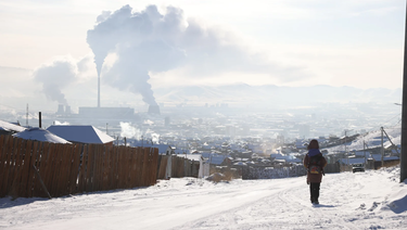 Girl walking in the snow carrying a backpack.