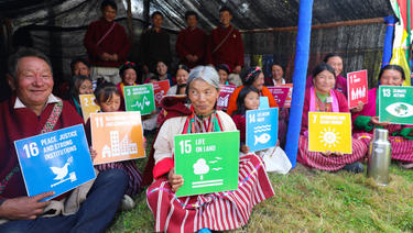 A group of people sitting on the grass holding SDG cards